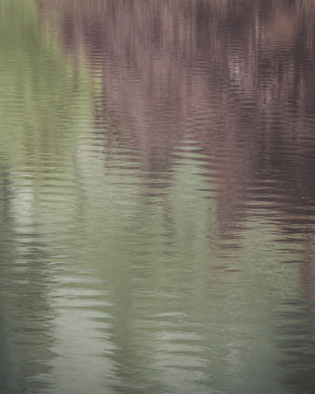 Still water surface with faint ripples in muted green and plum tones